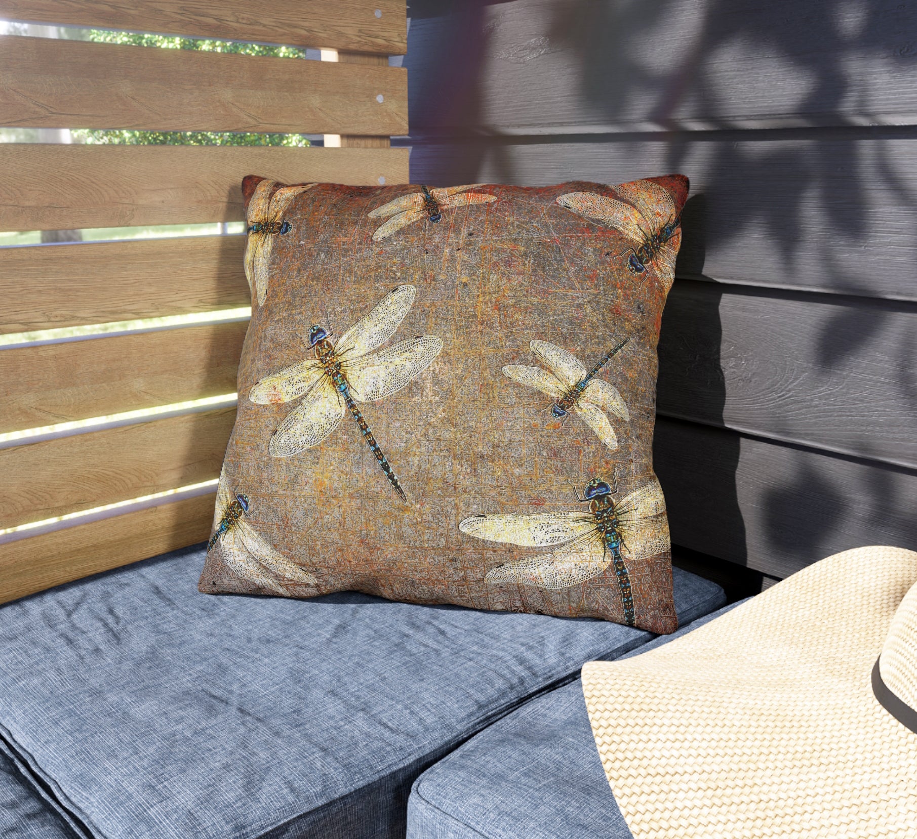 Decorative pillow with dragonfly design on a cushioned chair outdoors.
