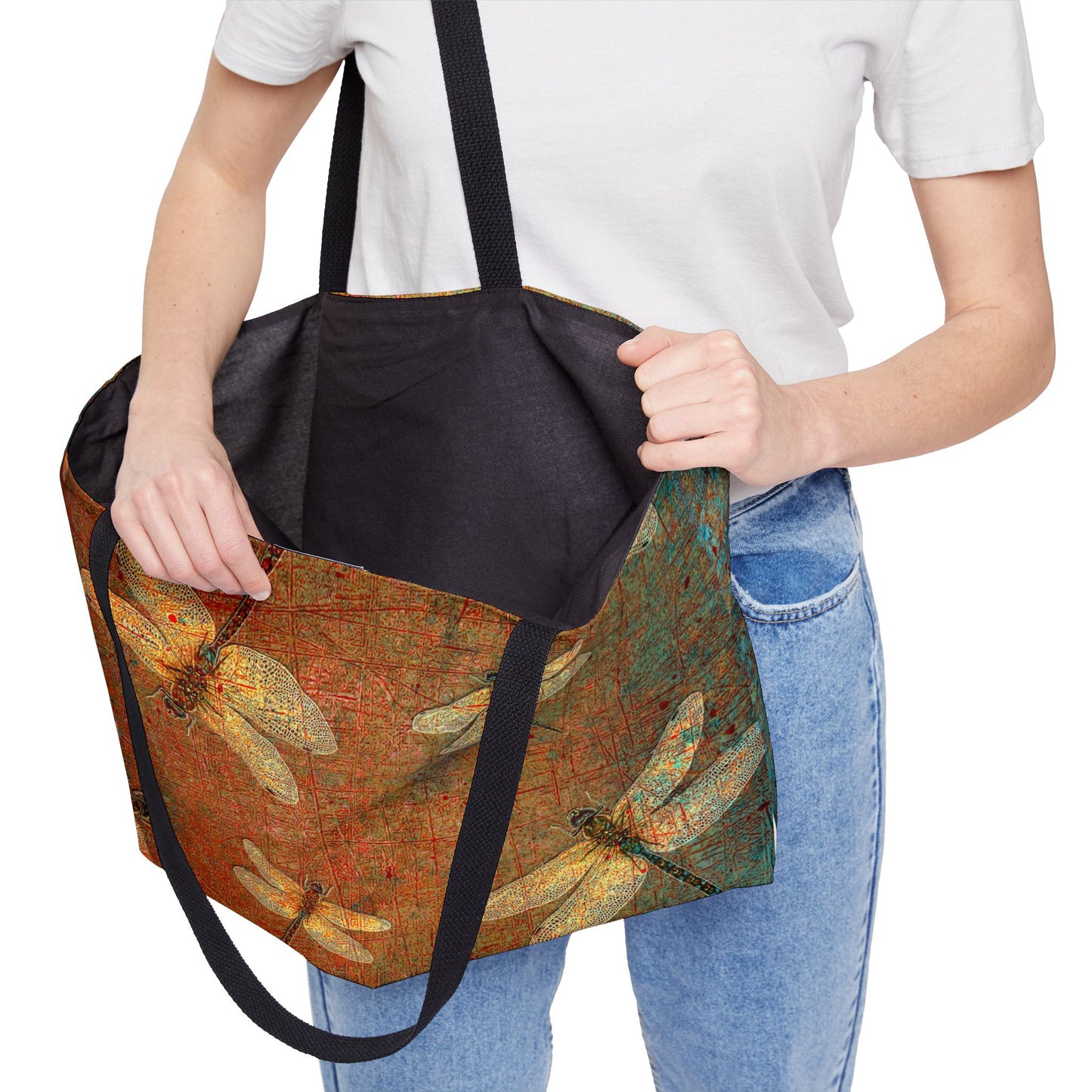 Person holding a tote bag with dragonfly design on a brown background with black liner