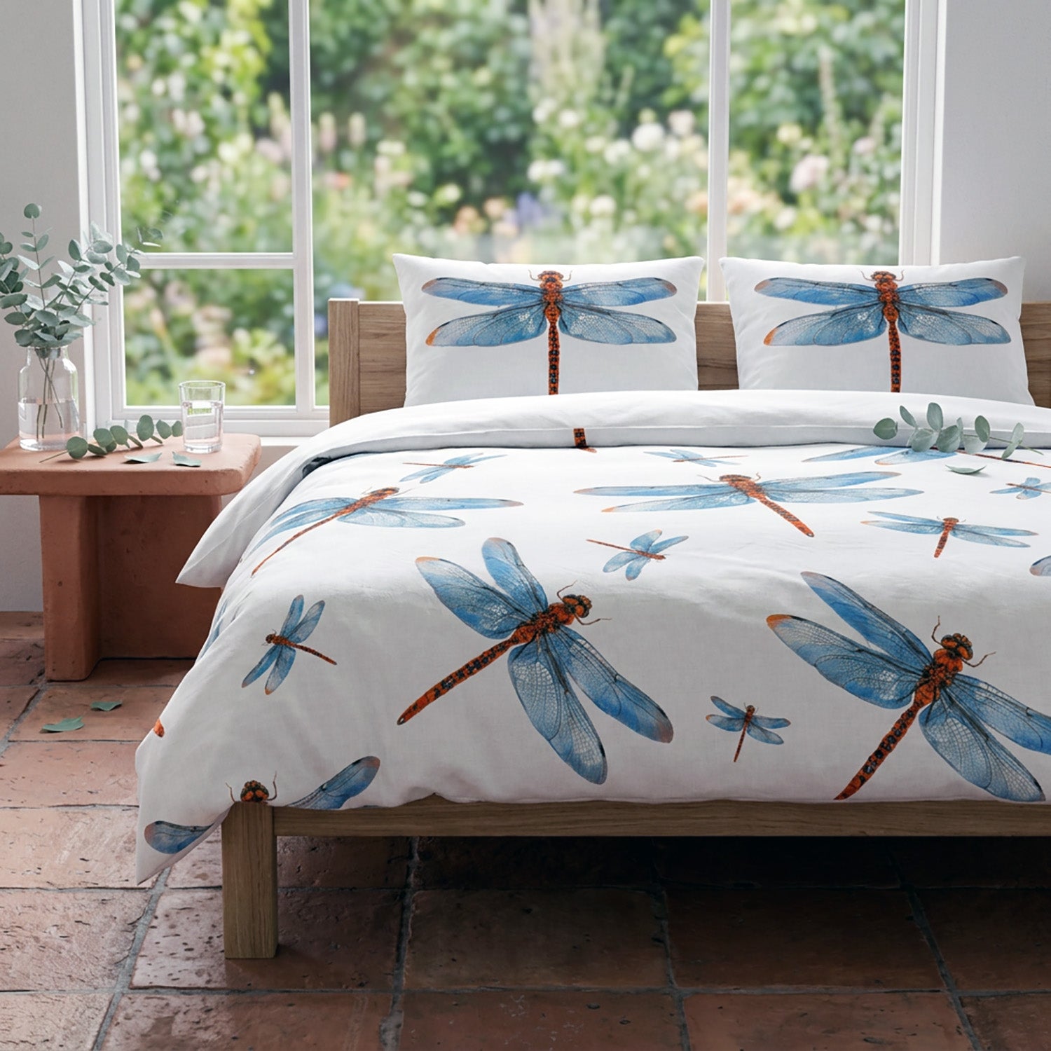 Bedding set with dragonfly design in a room with large windows showing greenery.
