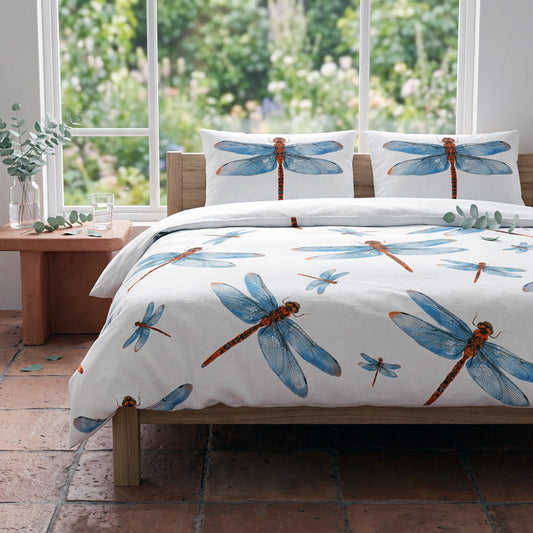 Bedding set with dragonfly design in a room with large windows showing greenery.