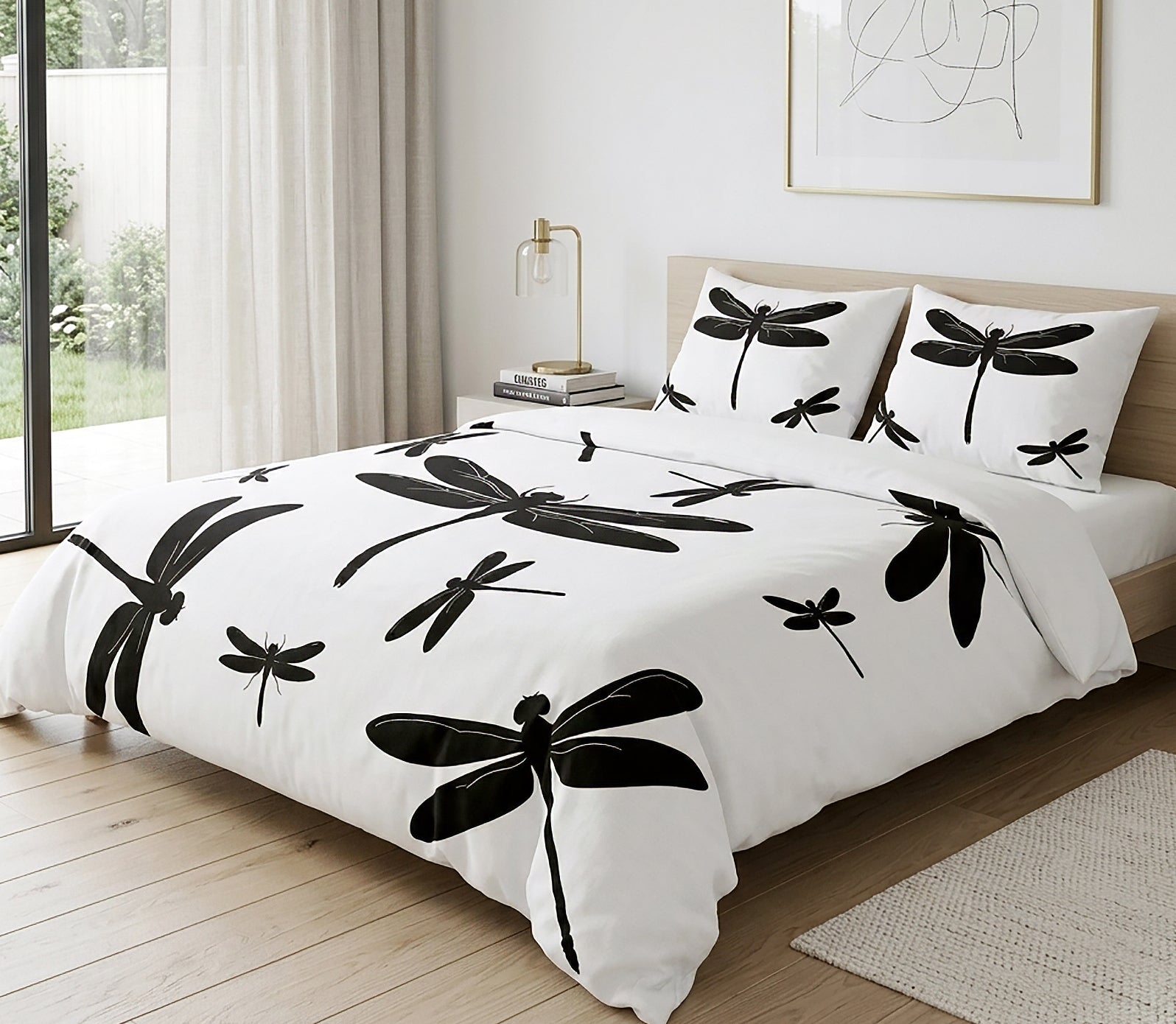 A bed dressed in a white duvet cover and matching pillowcases with large black dragonfly silhouettes, styled in a bright bedroom with wood flooring, a window, and a bedside lamp.