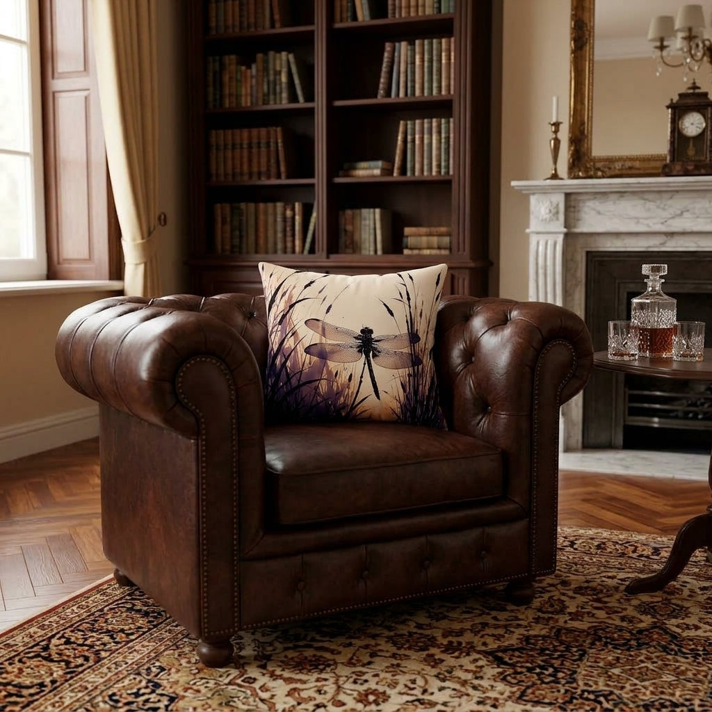 A brown leather Chesterfield armchair in a classic living room setting, featuring a decorative throw pillow with a dragonfly print on a beige background.