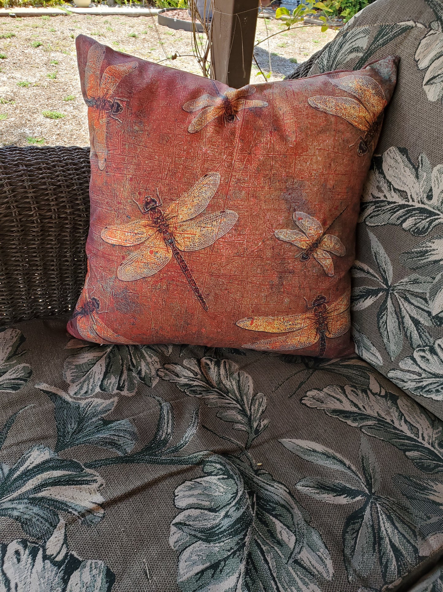 Decorative pillow with dragonfly pattern on a wicker chair with floral pattern