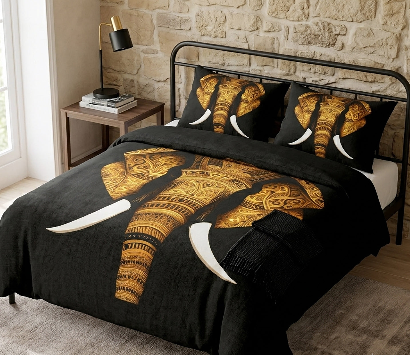 A bed dressed in a black bedding set featuring a large gold-patterned elephant design and two matching pillowcases, styled in a bedroom with a stone wall, bedside table, and lamp.
