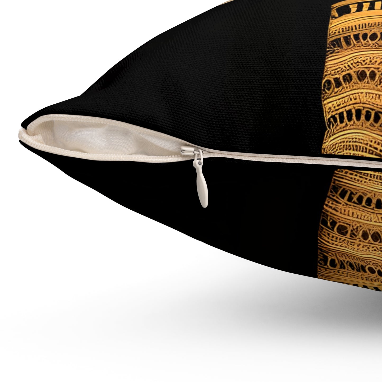 Close-up of a black throw pillow with a decorative gold and brown patterned panel on the right side and a white zipper track.