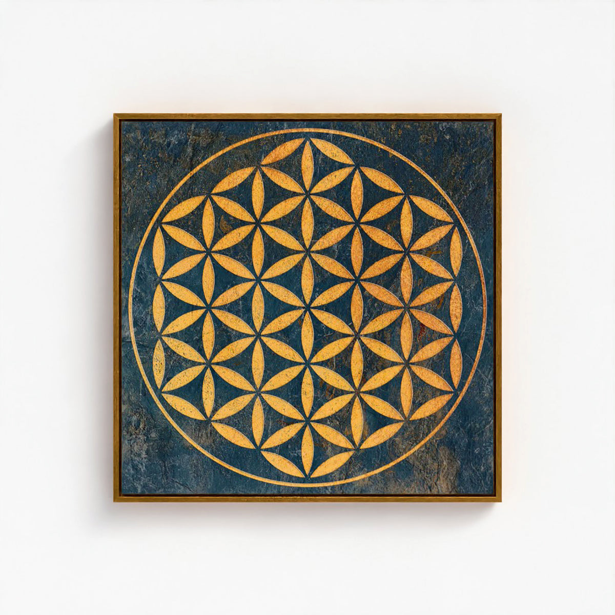 Square framed wall art featuring a golden geometric flower-of-life pattern on a distressed dark blue background, shown hanging on a white wall.