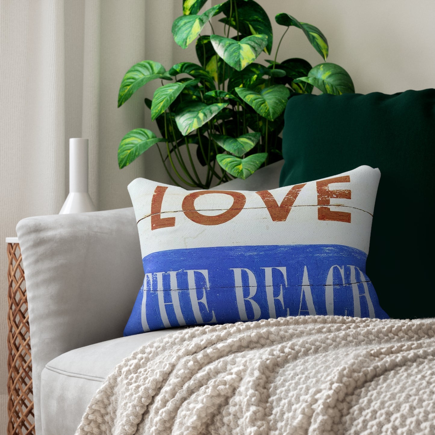 Decorative pillow with 'LOVE THE BEACH' text on a couch with a plant in the background