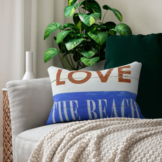 Decorative pillow with 'LOVE THE BEACH' text on a couch with a plant in the background