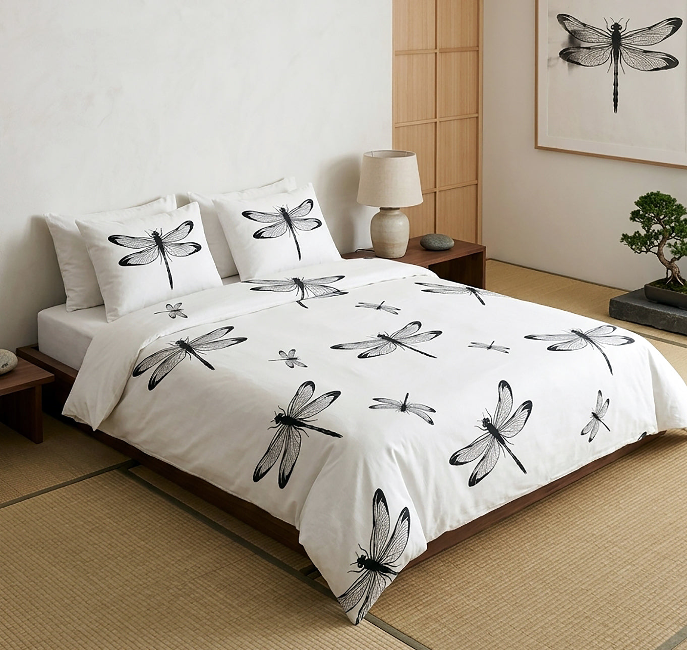 A Japanese-style bed dressed in a white bedding set with black dragonfly prints, styled in a minimalist room with a wooden floor, bedside table, and a matching dragonfly wall art print.