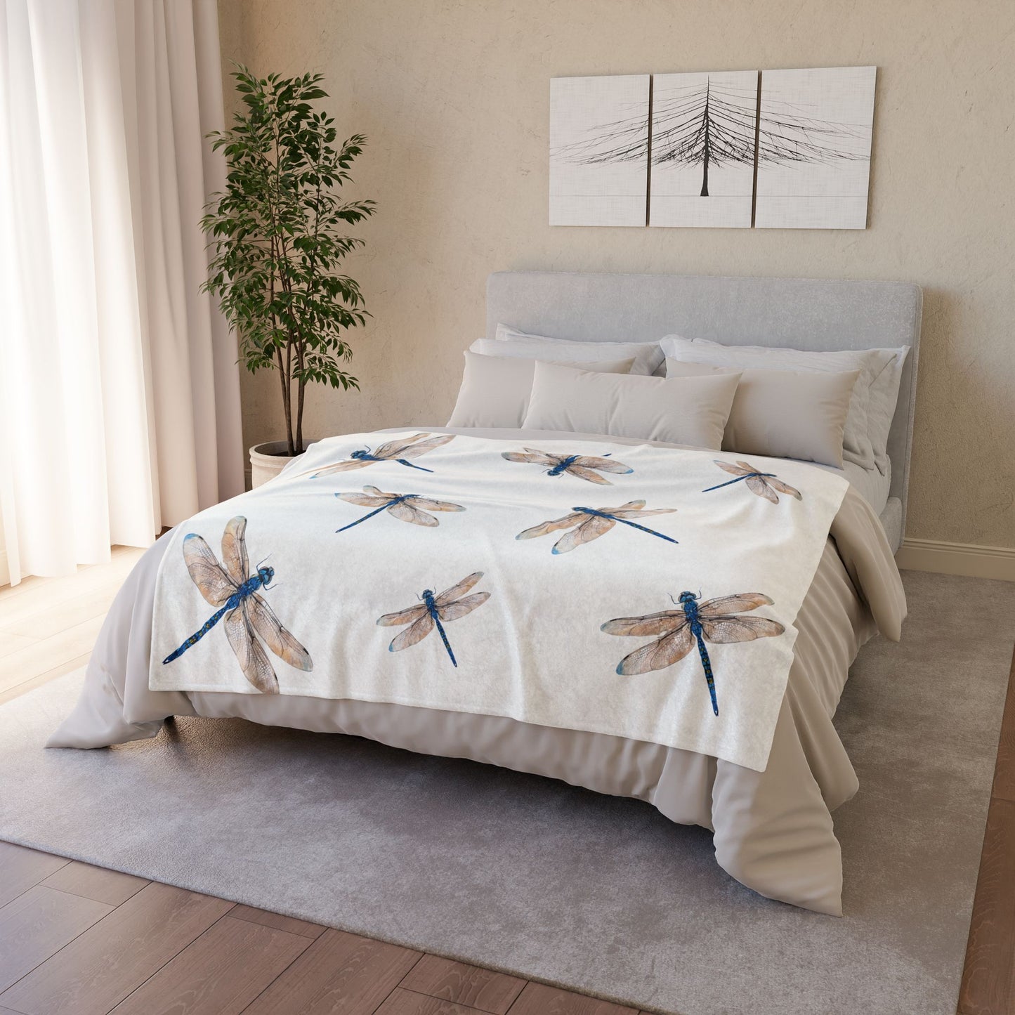A bed dressed in a light beige duvet cover and matching pillow shams, featuring a printed pattern of blue and brown dragonflies, styled in a bright bedroom setting.