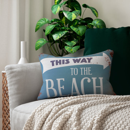 Decorative pillow with 'This Way to the Beach' text on a couch with a plant in the background
