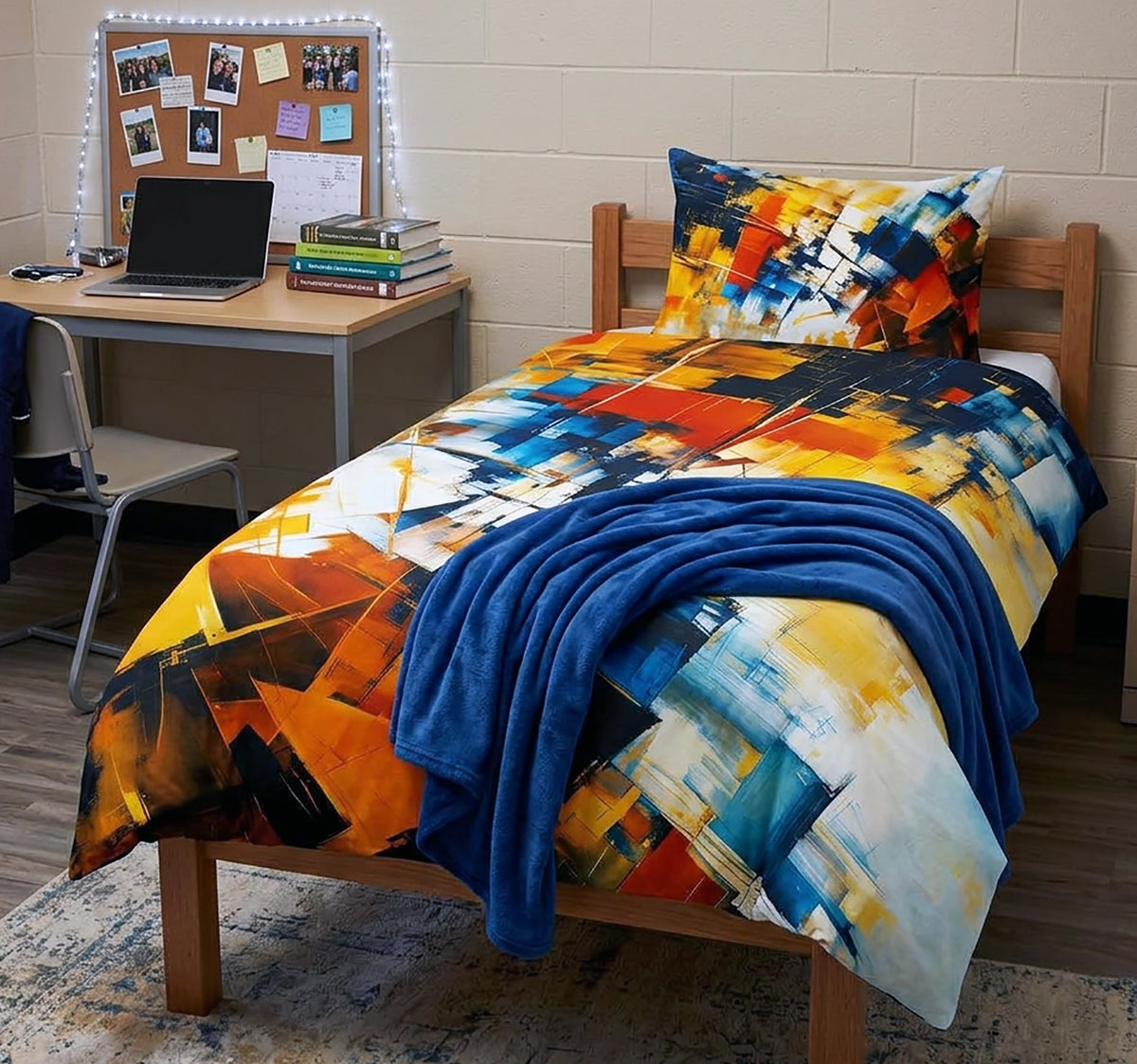 A single bed dressed in a colorful abstract print bedding set with a matching pillowcase and a solid blue throw blanket, shown in a dorm room setting with a desk and laptop.